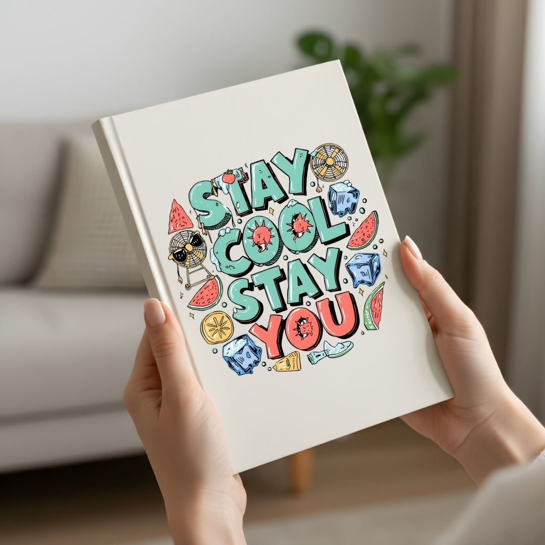 Person holding a notebook with 'Stay Cool Stay You' design in a home setting