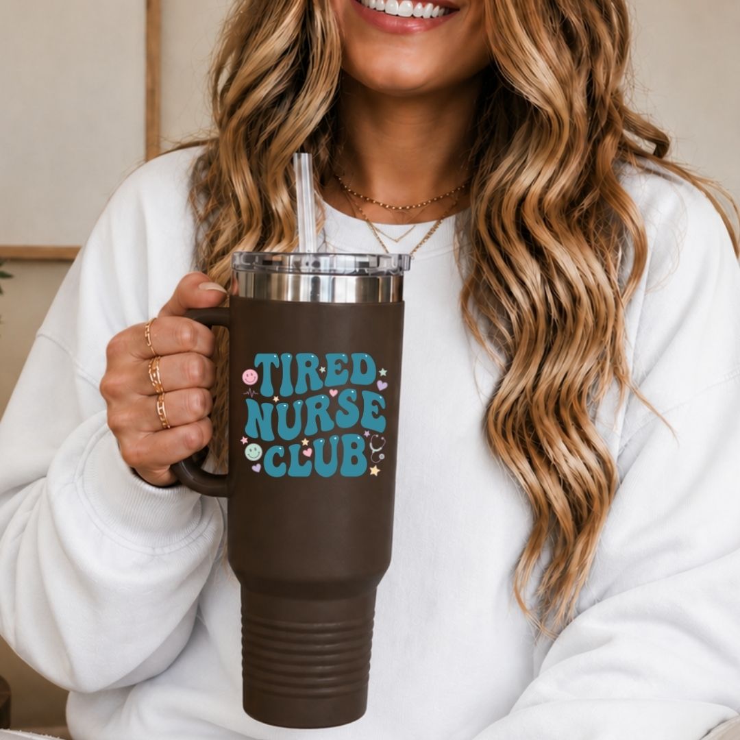Person holding a brown mug with 'Tired Nurse Club' text, smiling.