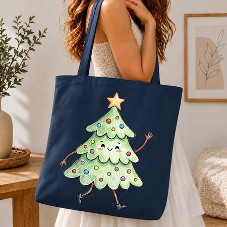 A navy blue canvas tote bag with a cartoon Christmas tree graphic, carried by a woman in a white dress in a cozy indoor setting.