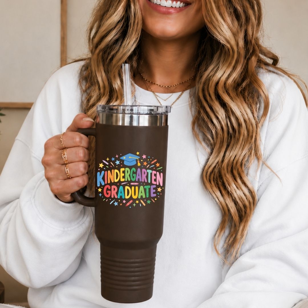 Person holding a brown mug with 'Kindergarten Graduate' text and colorful design.