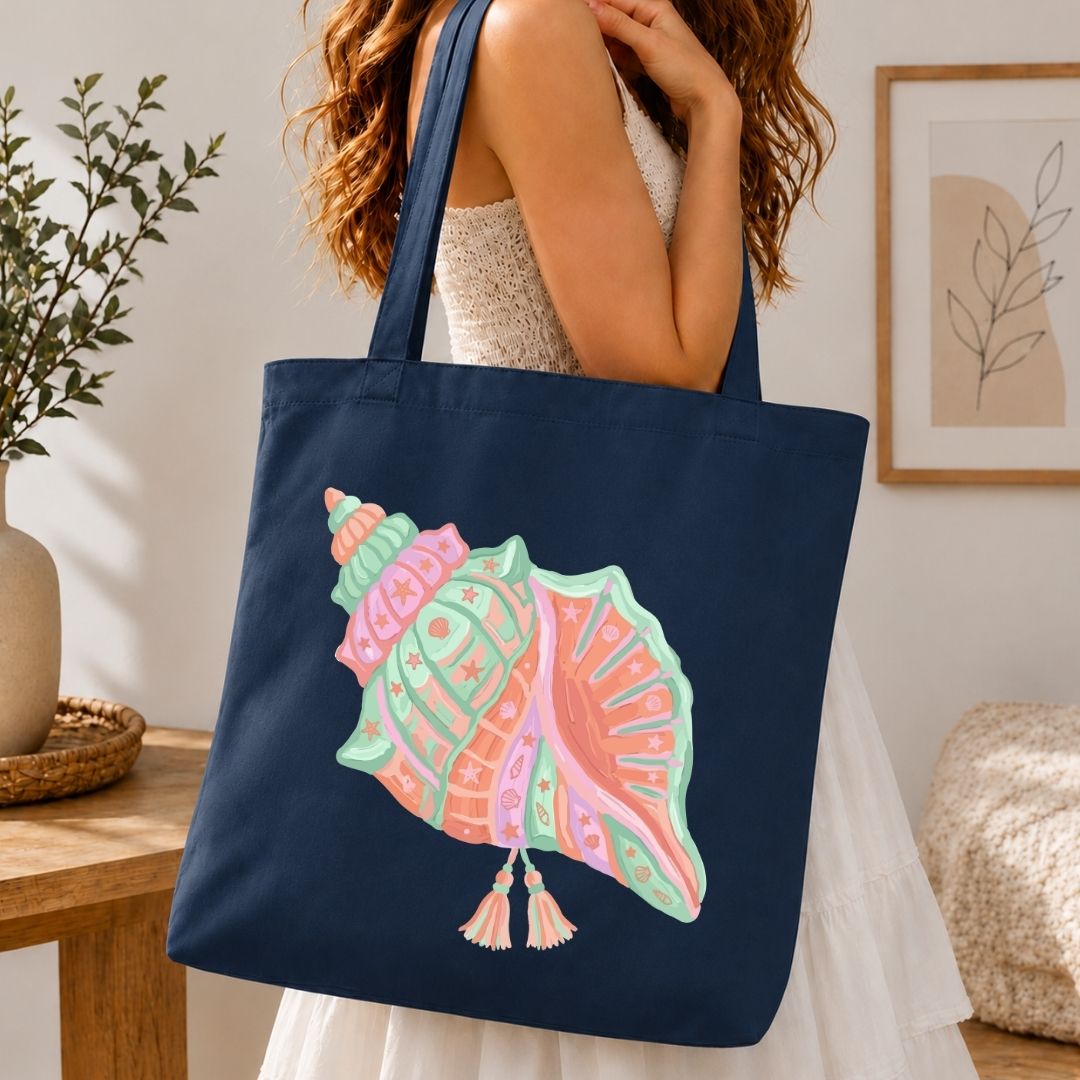 Navy tote bag with a colorful shell design held by a person in a home setting.