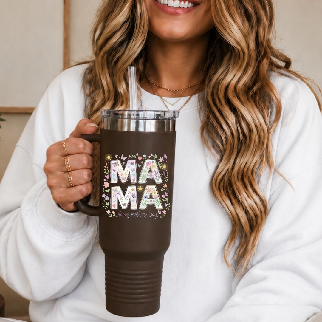 Person holding a brown mug with 'MAMA' and flowers design, smiling.