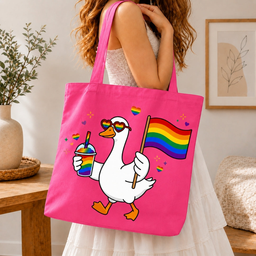 Person holding a pink tote bag with a cartoon goose holding a rainbow flag and a drink.