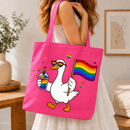 Person holding a pink tote bag with a cartoon goose holding a rainbow flag and a drink.