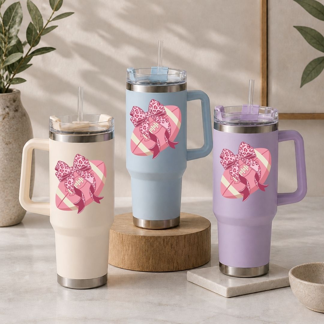 Three insulated travel mugs with decorative bows on a neutral background