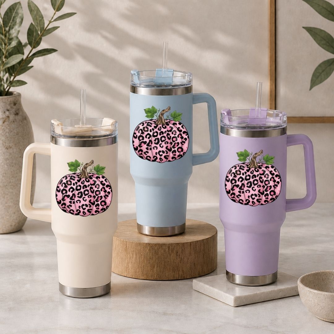 Three insulated mugs with leopard print pumpkins on a neutral background