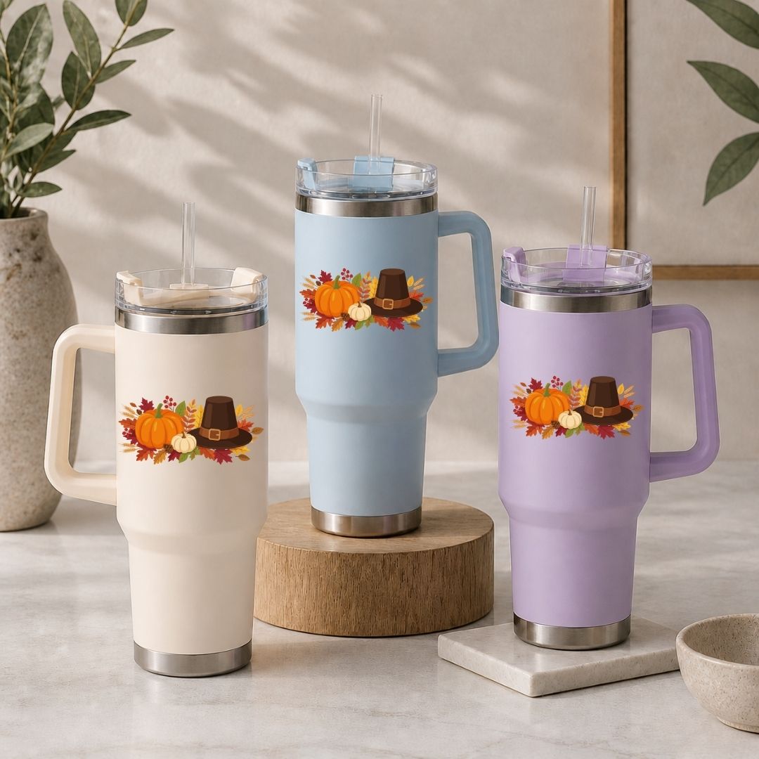 Three insulated travel mugs with autumn-themed designs on a neutral background