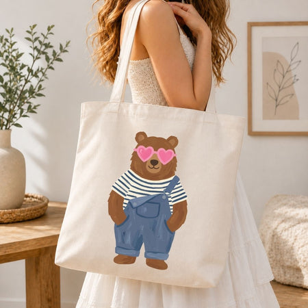 Person holding a tote bag with a bear illustration in a home setting