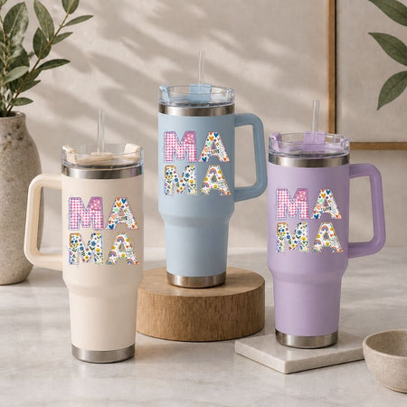 Three insulated mugs with 'MAMA' text in colorful letters on a neutral background.