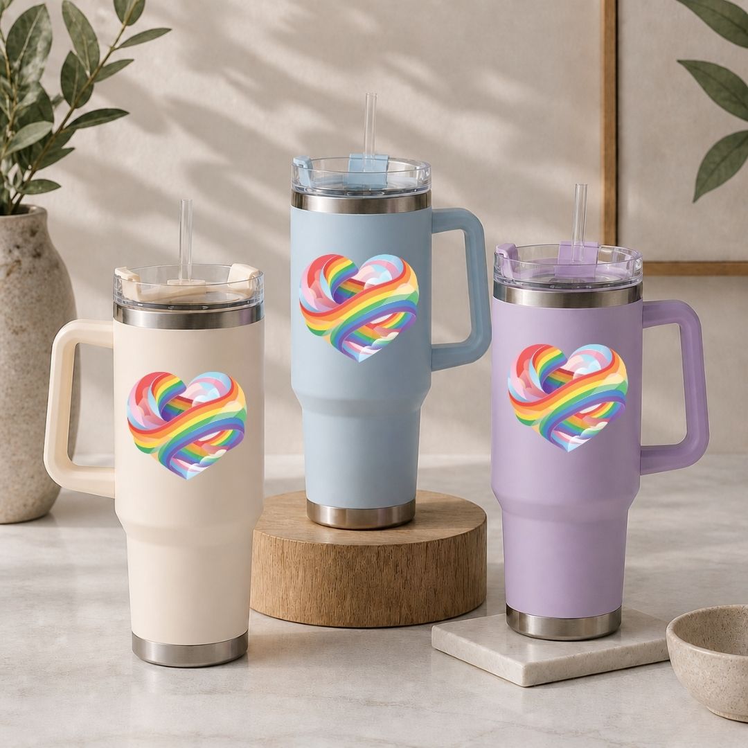 Three insulated travel mugs with rainbow heart designs on a neutral background.