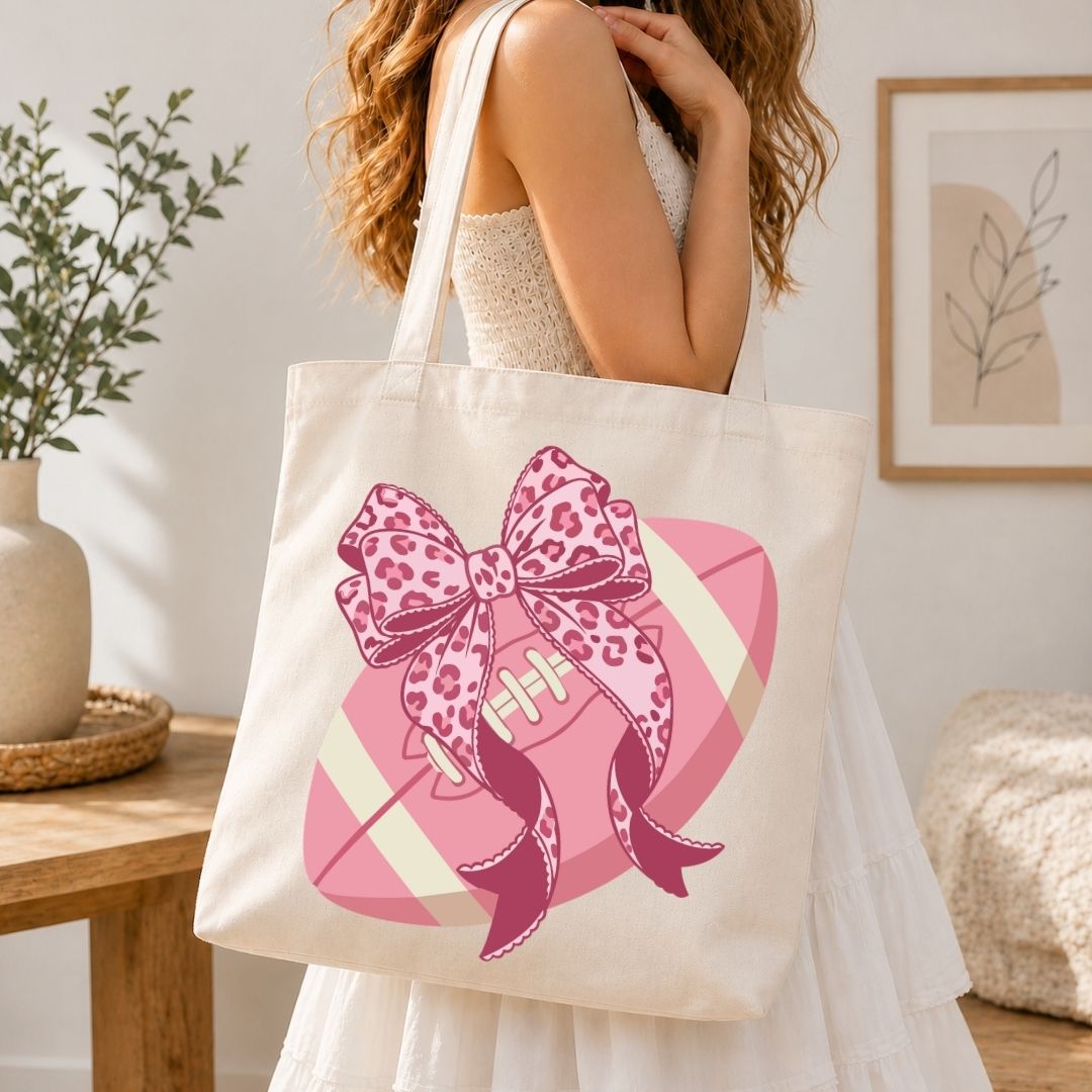 Person holding a tote bag with a pink bow design in a home setting