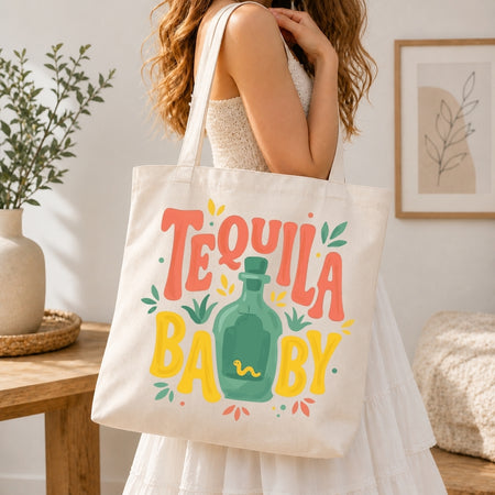 Person holding a tote bag with 'Tequila Baby' design in a home setting