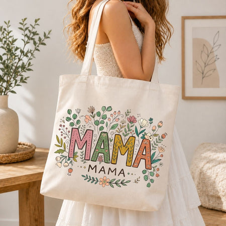 Person holding a tote bag with 'MAMA' design in a home setting