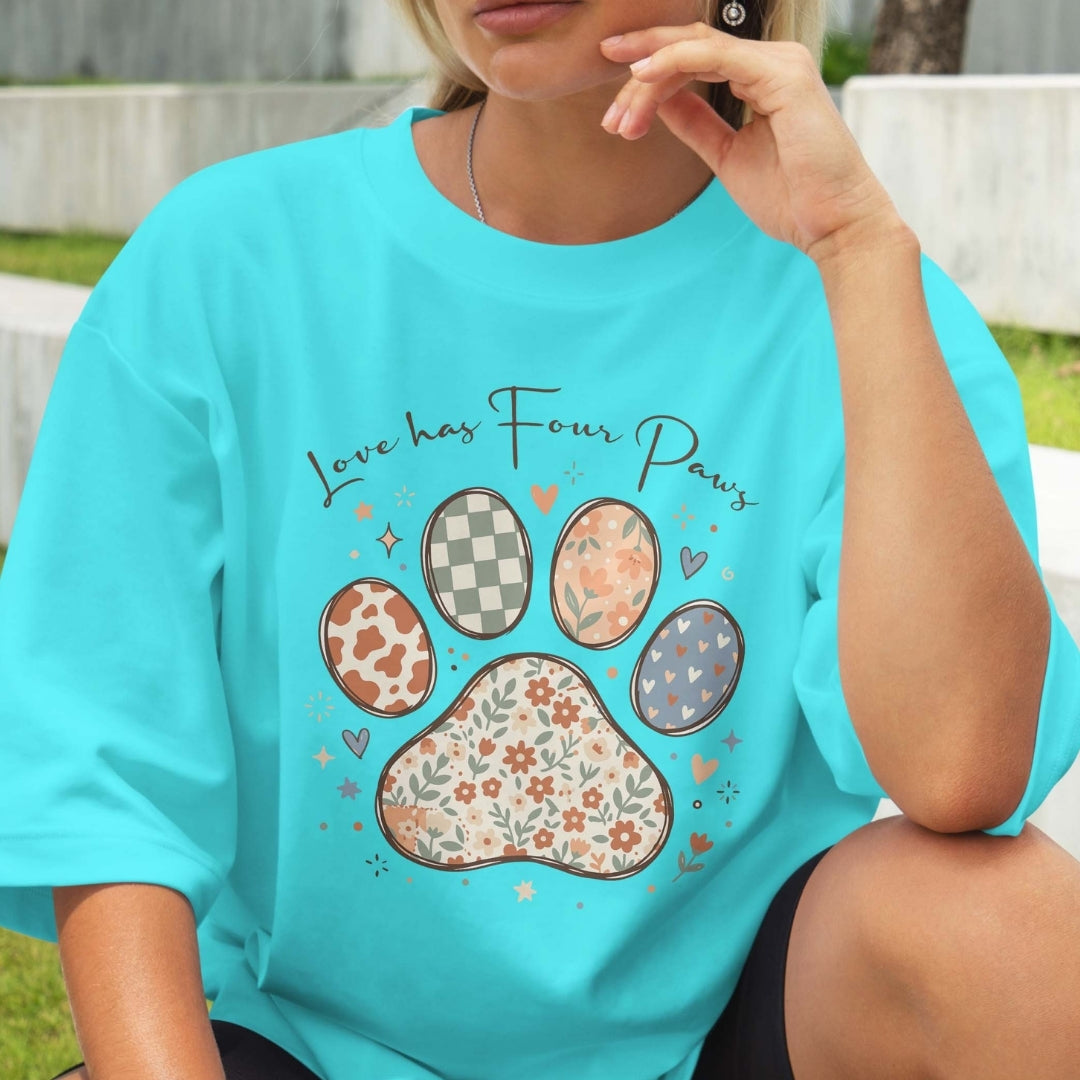 Person wearing a turquoise t-shirt with paw print design and 'Love has Four Paws' text.