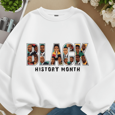 White sweatshirt with 'Black History Month' design featuring various faces, on a neutral background.