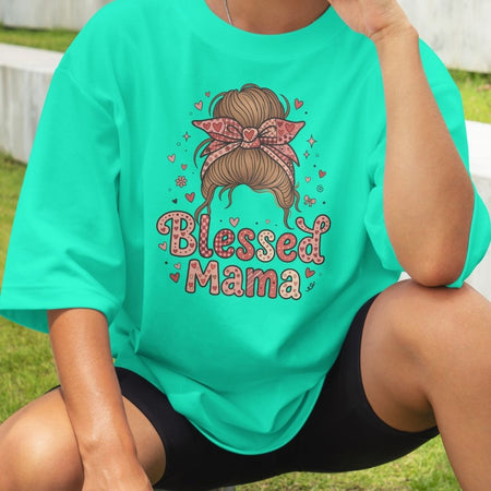 Person wearing a teal t-shirt with 'Blessed Mama' design outdoors.