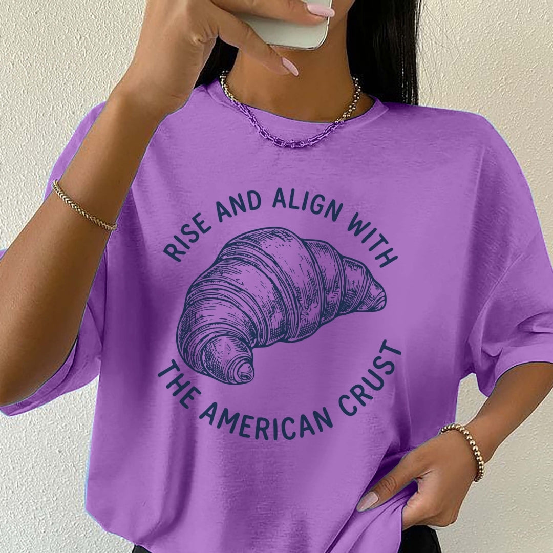 Person wearing a purple t-shirt with a croissant graphic and text.