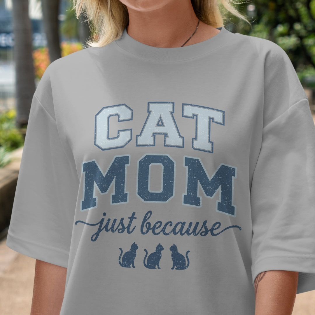 Person wearing a gray t-shirt with 'CAT MOM just because' text and cat illustrations.