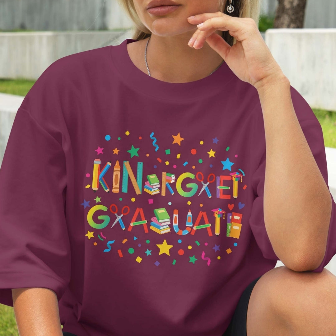 Person wearing a purple t-shirt with colorful 'Kindergarten Graduate' text and graphics.