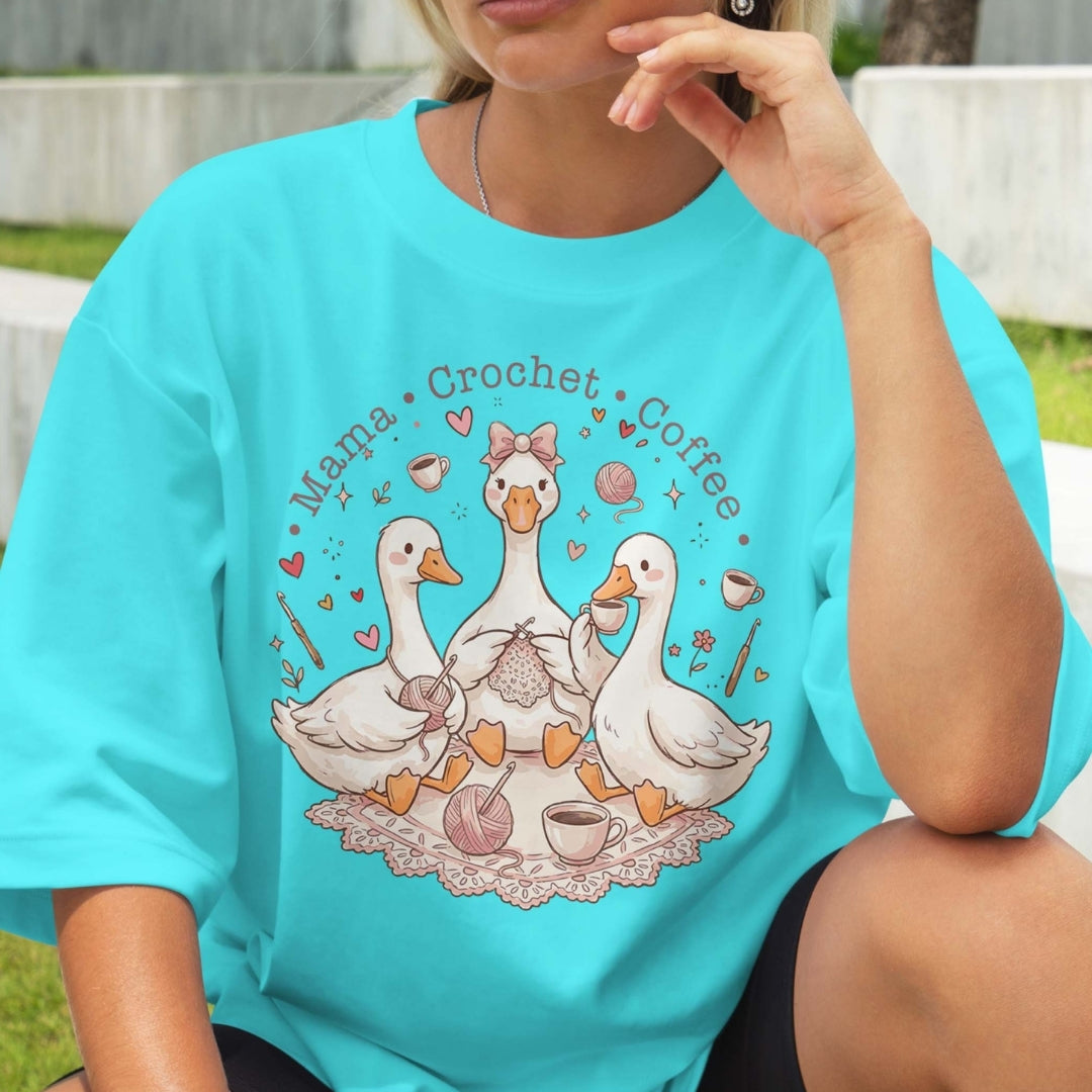 Person wearing a turquoise t-shirt with a graphic of ducks, text, and coffee cups.