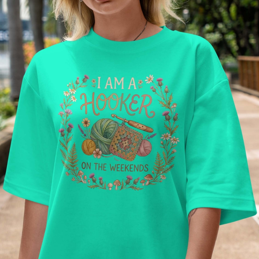 Person wearing a teal t-shirt with a crochet-themed graphic and text.
