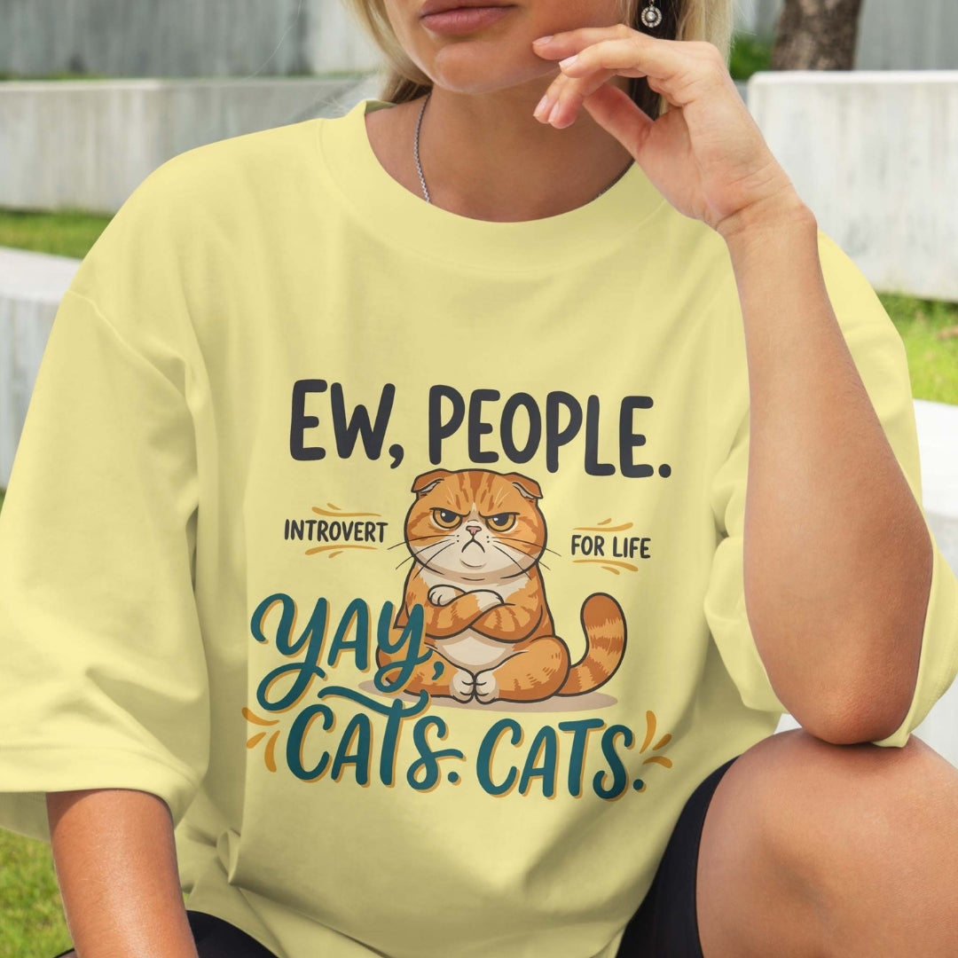 Person wearing a yellow t-shirt with a cat graphic and text.