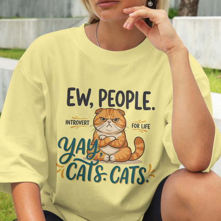 Person wearing a yellow t-shirt with a cat graphic and text.