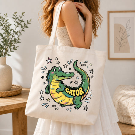 Person holding a tote bag with a cartoon alligator design and 'GATOR' text.