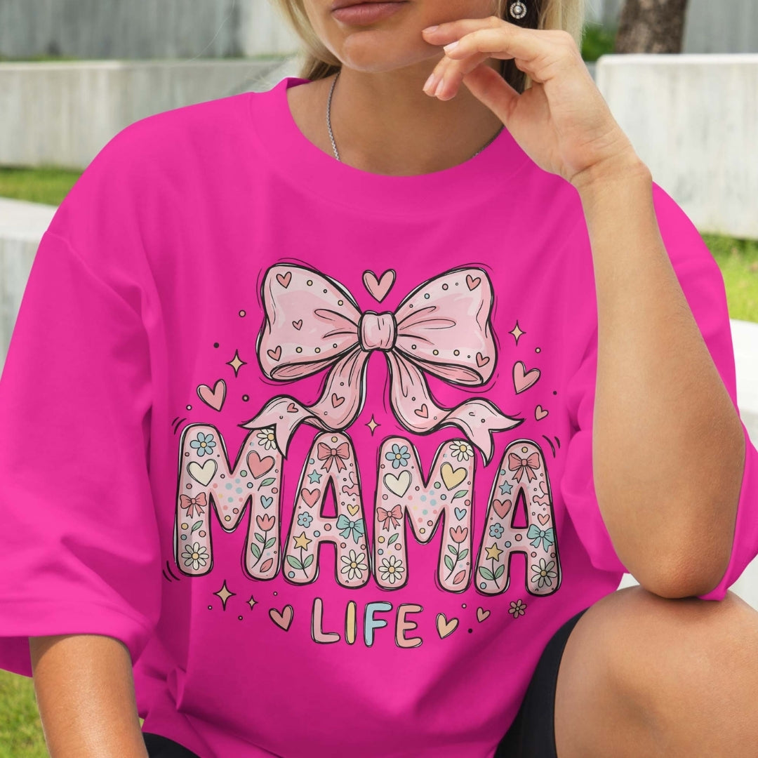 Person wearing a pink t-shirt with 'MAMA LIFE' design featuring a bow and hearts.