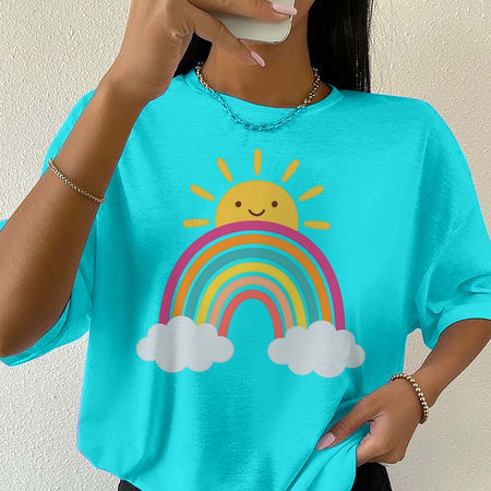 Person wearing a turquoise t-shirt with a rainbow and sun design.