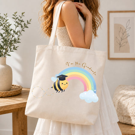 Person holding a tote bag with a bee and rainbow design in a home setting
