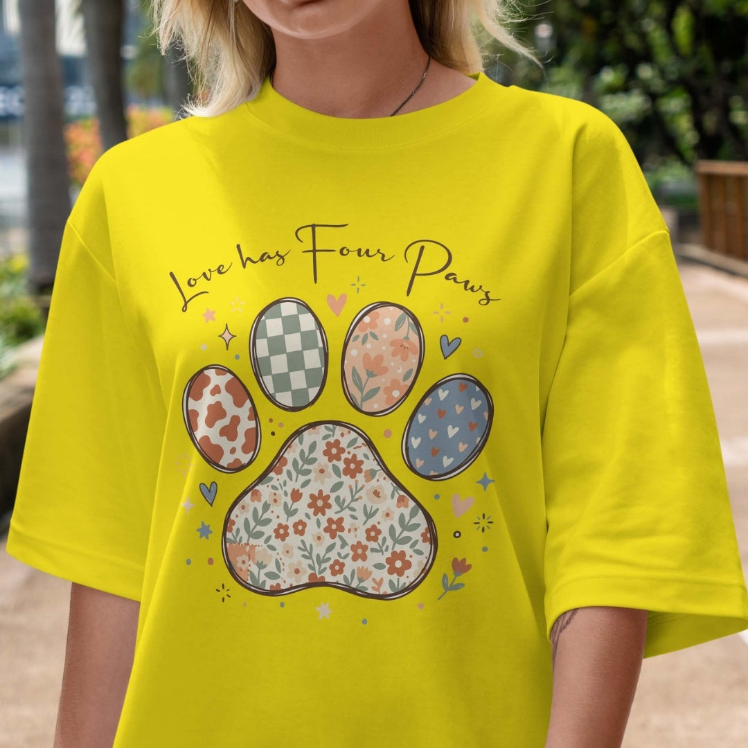 Person wearing a yellow t-shirt with paw print design and text 'Love has Four Paws'.