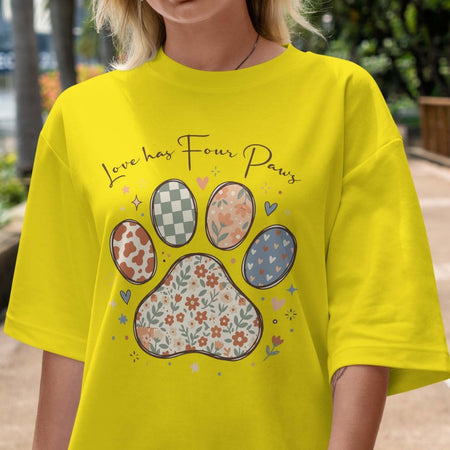 Person wearing a yellow t-shirt with paw print design and text 'Love has Four Paws'.