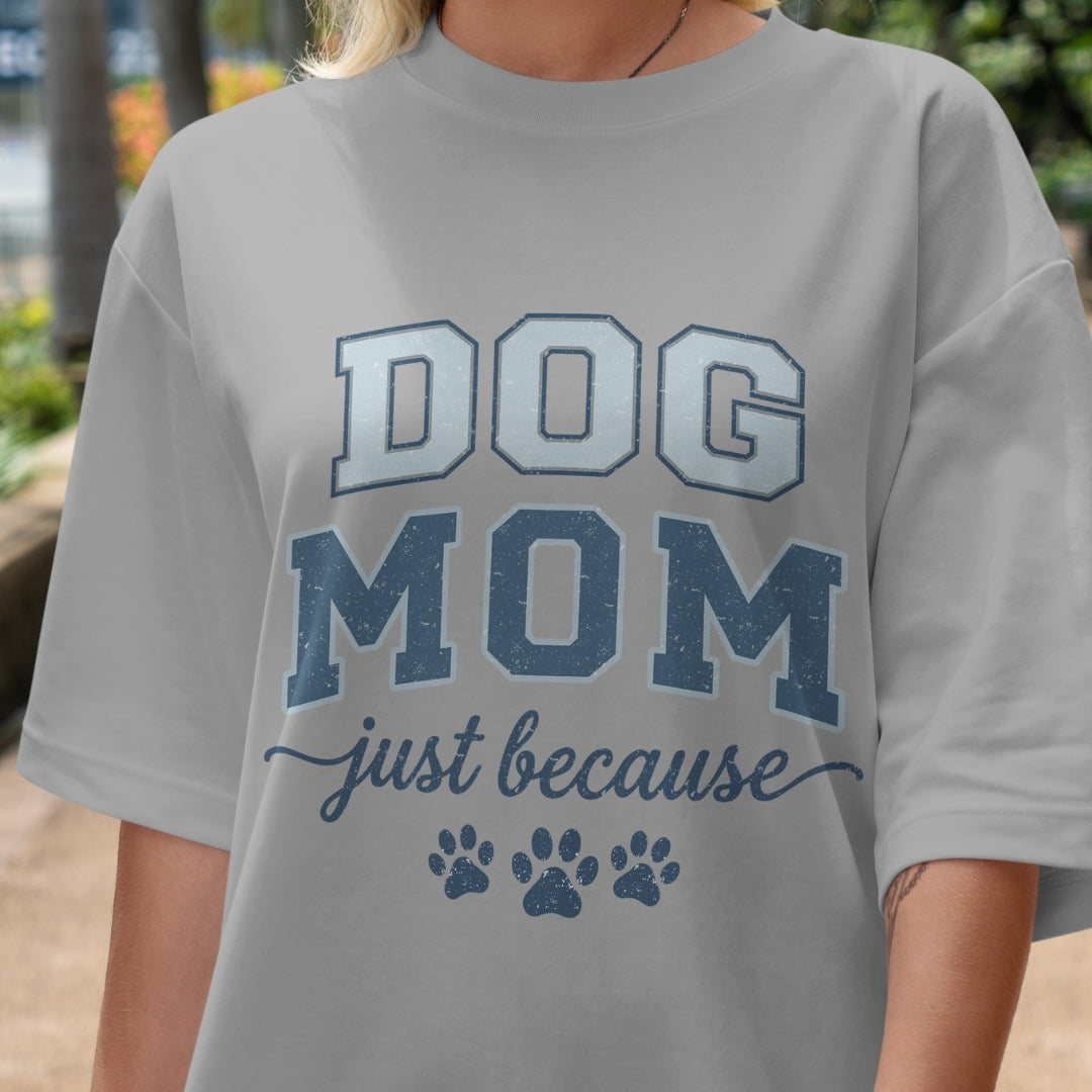 Gray t-shirt with 'DOG MOM just because' text and paw prints on a blurred outdoor background