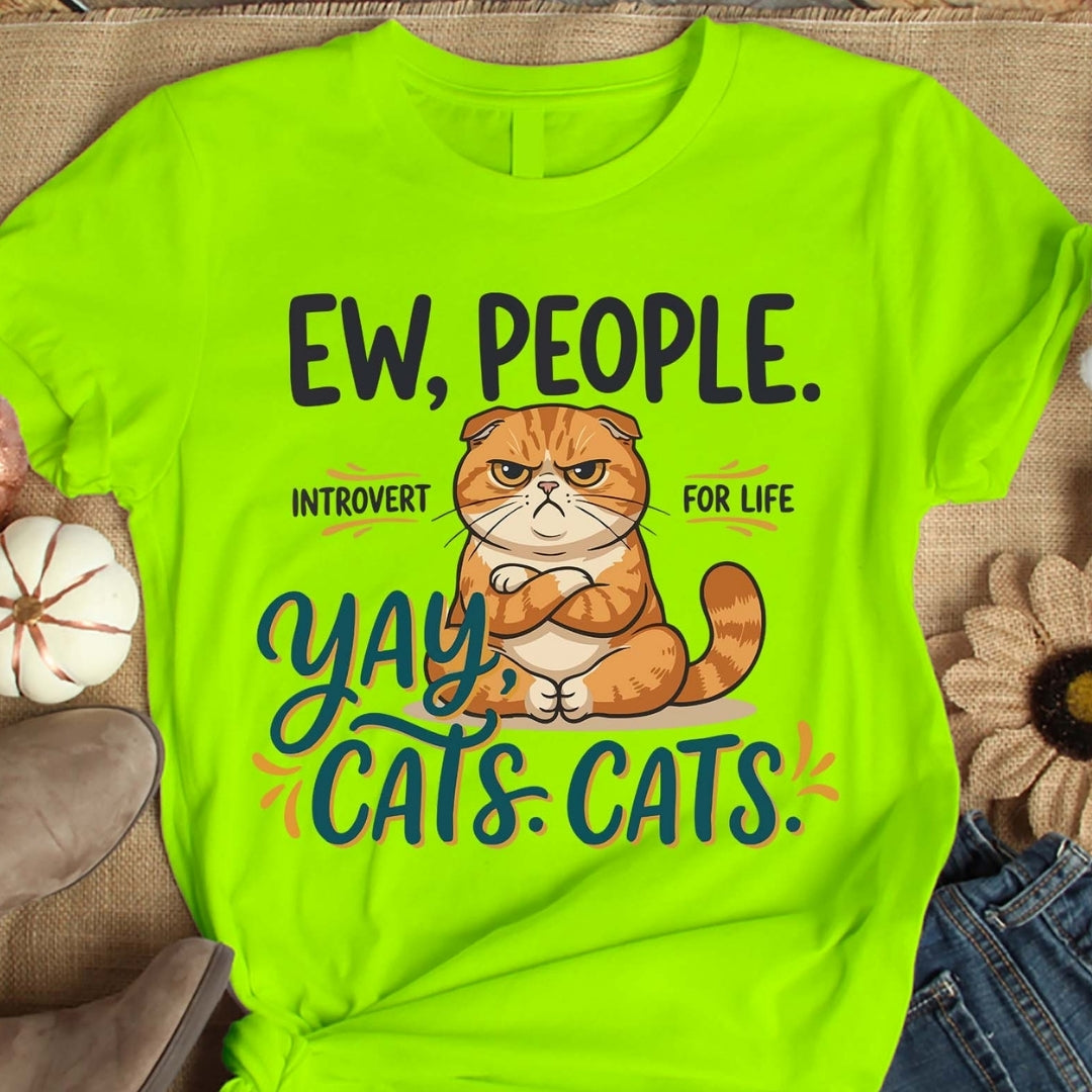 Bright green t-shirt with a cat graphic and text on a wooden surface.
