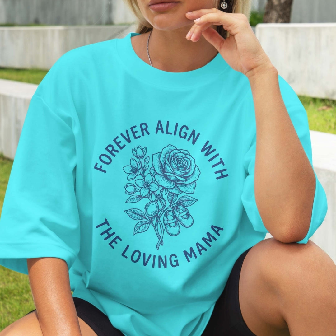 Person wearing a turquoise t-shirt with floral design and text outdoors.