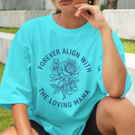 Person wearing a turquoise t-shirt with floral design and text outdoors.