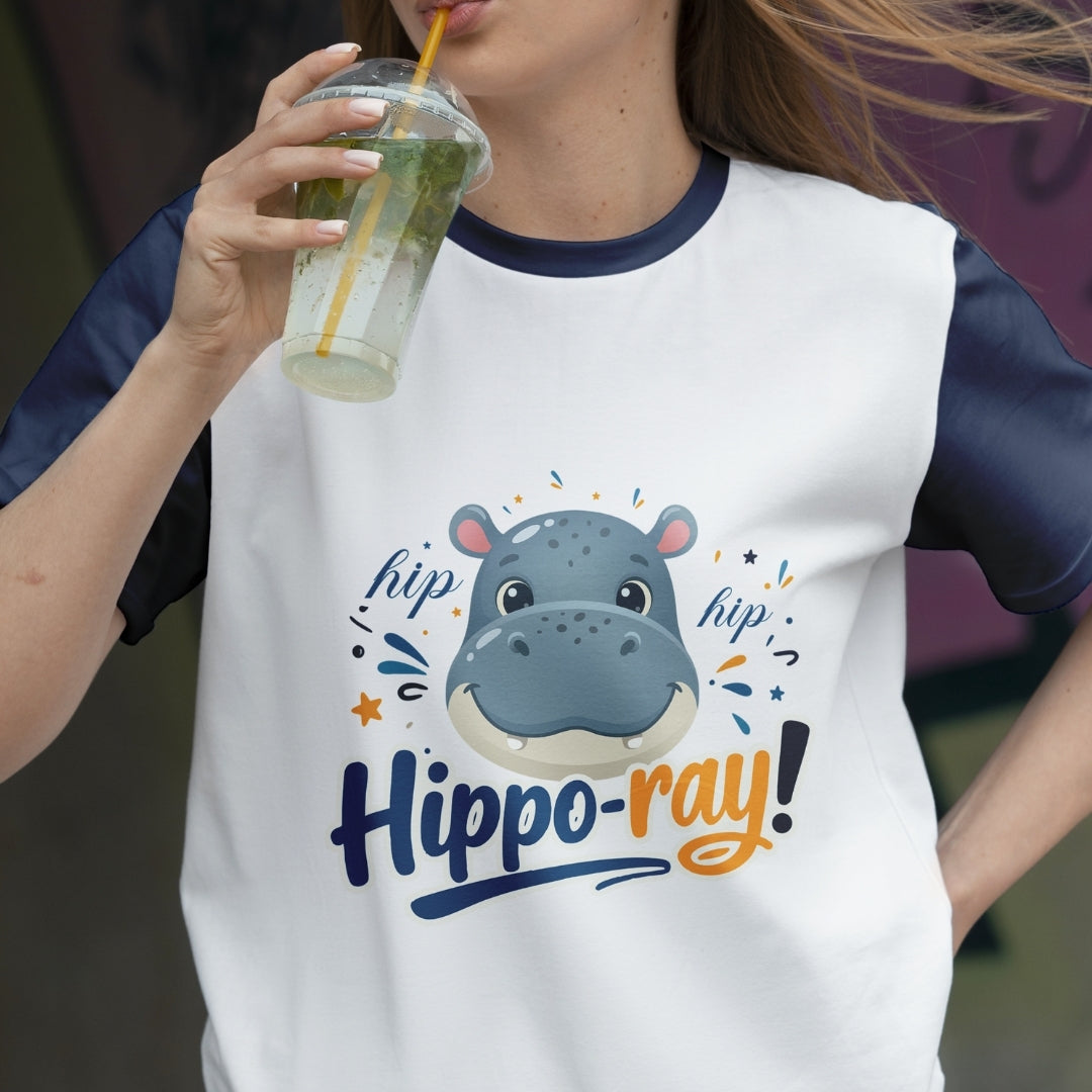 Person wearing a t-shirt with a hippo graphic and 'hipp-o-ray!' text, holding a drink.