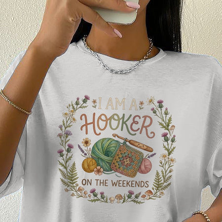Person wearing a white t-shirt with a crochet-themed design and text.
