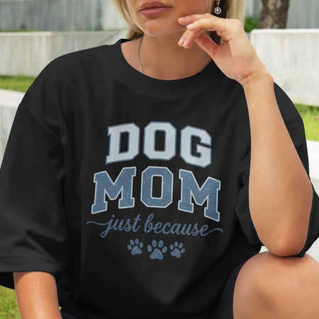 Person wearing a black 'DOG MOM just because' shirt outdoors.