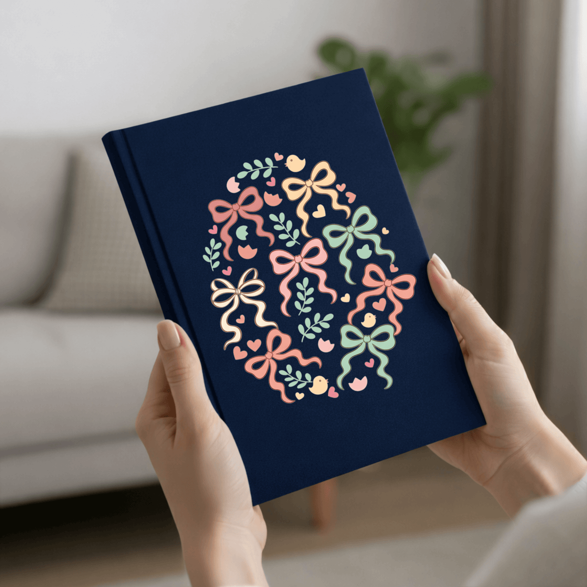 Navy blue notebook with colorful bow design held by hands in a home setting
