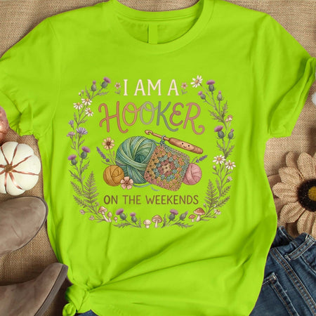 Green t-shirt with crochet-themed design and text on a textured surface.