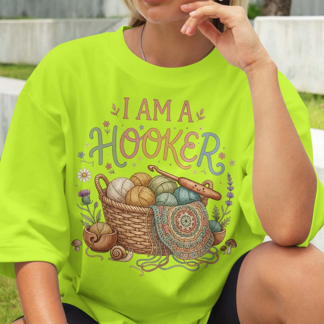 Person wearing a bright green t-shirt with 'I AM A HOOKER' design featuring yarn and crochet elements.