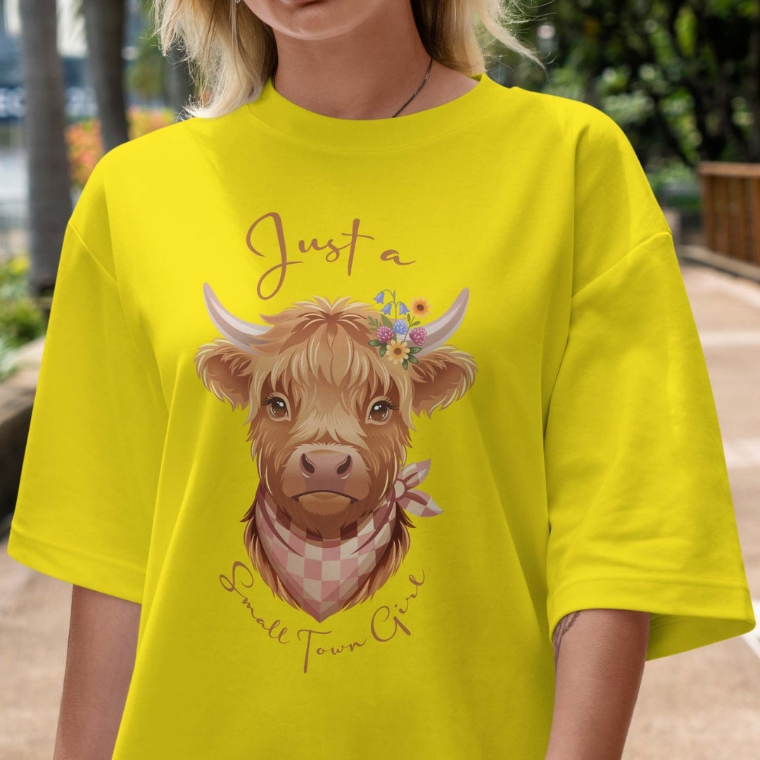 Person wearing a yellow t-shirt with a cow graphic and text outdoors.