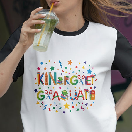 Person wearing a white t-shirt with colorful 'KINDERGARTEN GRADUATE' text, drinking from a glass.