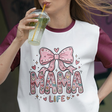 Person wearing a t-shirt with a 'Mama Life' design and holding a drink.