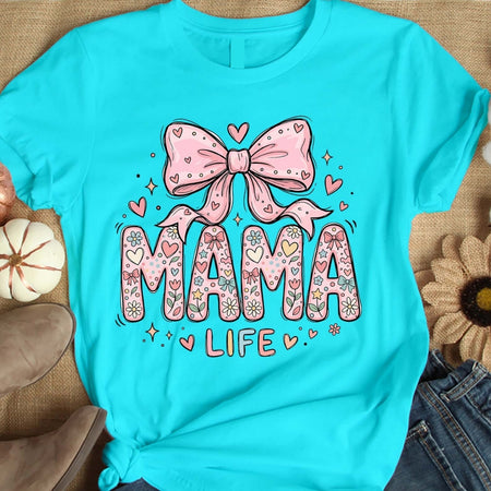 Turquoise t-shirt with 'MAMA LIFE' design featuring a pink bow and hearts on a textured surface.