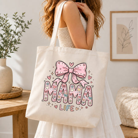 Person holding a tote bag with 'Mama Life' design in a home setting