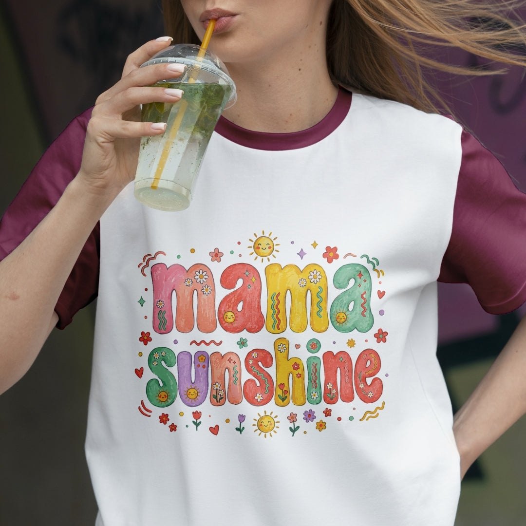 Woman drinking a refreshing beverage while wearing a retro white ringer t-shirt with maroon sleeves, printed with a colorful "Mama Sunshine" graphic.