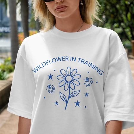 Person wearing a white t-shirt with blue floral design and text outdoors.